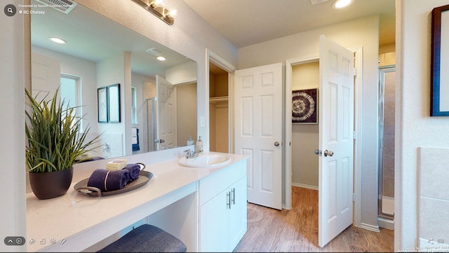 bathroom featuring hardwood / wood-style flooring, a shower with door, and vanity