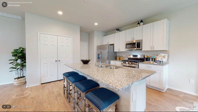 kitchen featuring a kitchen breakfast bar, appliances with stainless steel finishes, sink, white cabinetry, and a kitchen island with sink