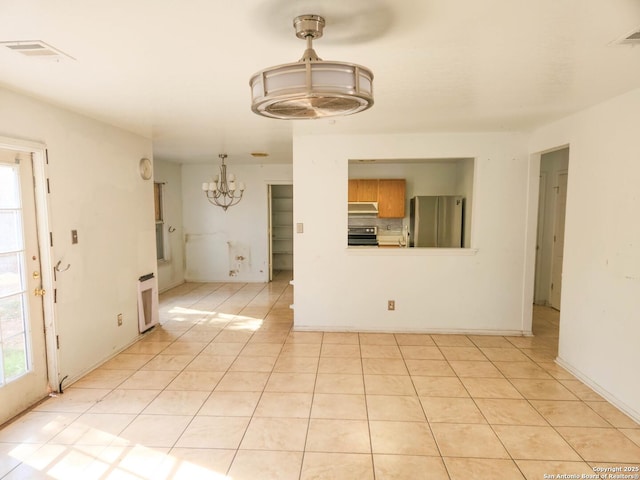 unfurnished living room with an inviting chandelier and light tile patterned flooring