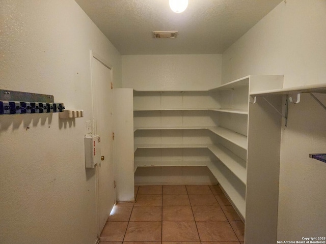 walk in closet with light tile patterned floors