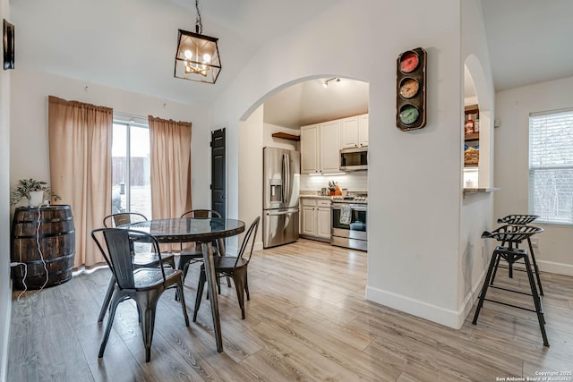 dining area featuring light hardwood / wood-style floors, lofted ceiling, and an inviting chandelier