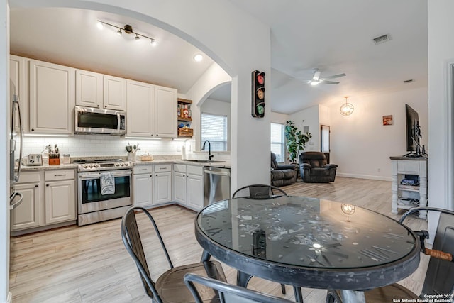 kitchen featuring white cabinets, lofted ceiling, stainless steel appliances, tasteful backsplash, and sink