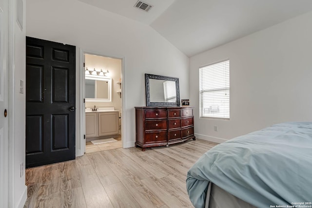 bedroom with sink, lofted ceiling, light hardwood / wood-style flooring, and ensuite bath