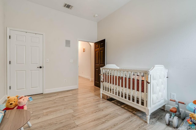 bedroom featuring light wood-type flooring and a nursery area