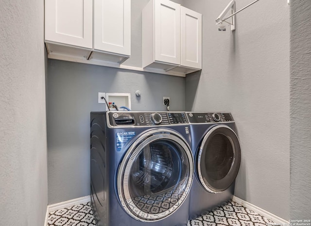 laundry room featuring washing machine and dryer, light tile patterned floors, and cabinets