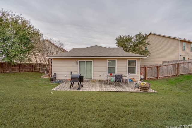 rear view of property featuring a wooden deck and a lawn