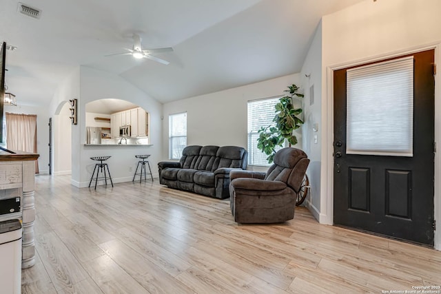 living room with ceiling fan, vaulted ceiling, and light wood-type flooring