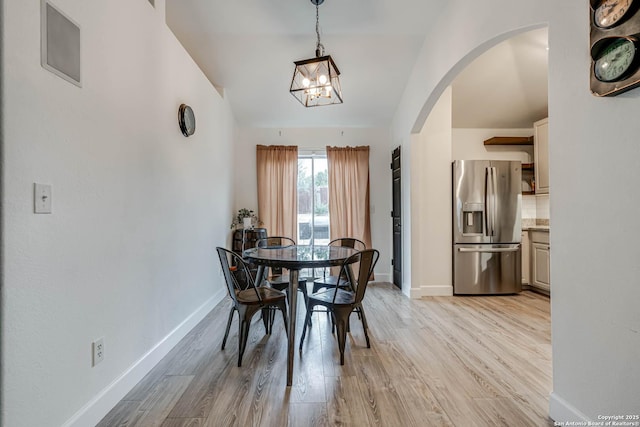 dining space featuring an inviting chandelier, light hardwood / wood-style floors, and lofted ceiling