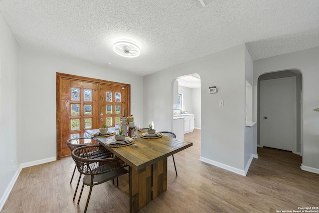 dining area with light hardwood / wood-style floors and a textured ceiling