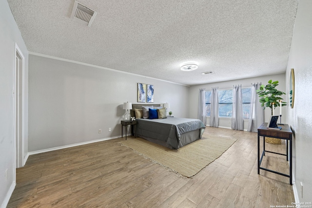 bedroom with hardwood / wood-style flooring, crown molding, and a textured ceiling