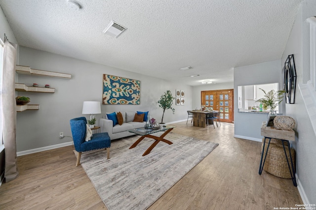 living room with light wood-type flooring and a textured ceiling