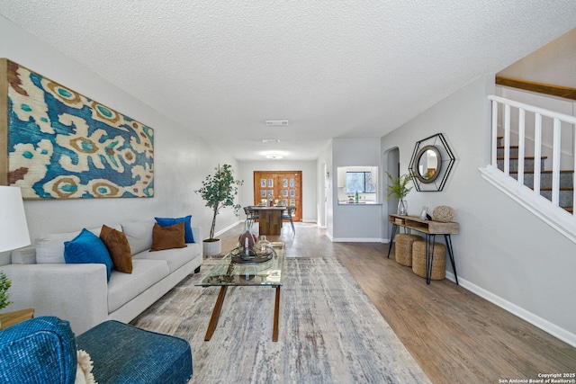 living room featuring light wood-type flooring and a textured ceiling