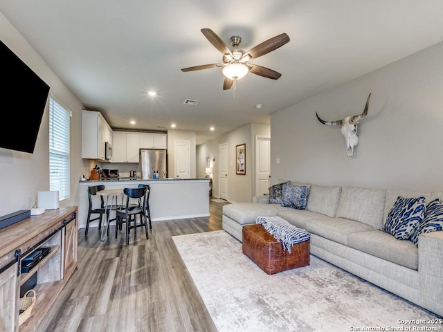 living room featuring light wood-type flooring and ceiling fan