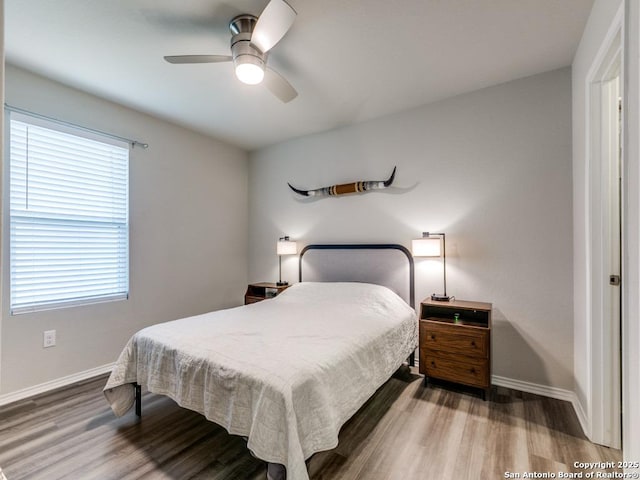 bedroom featuring ceiling fan, multiple windows, and hardwood / wood-style floors