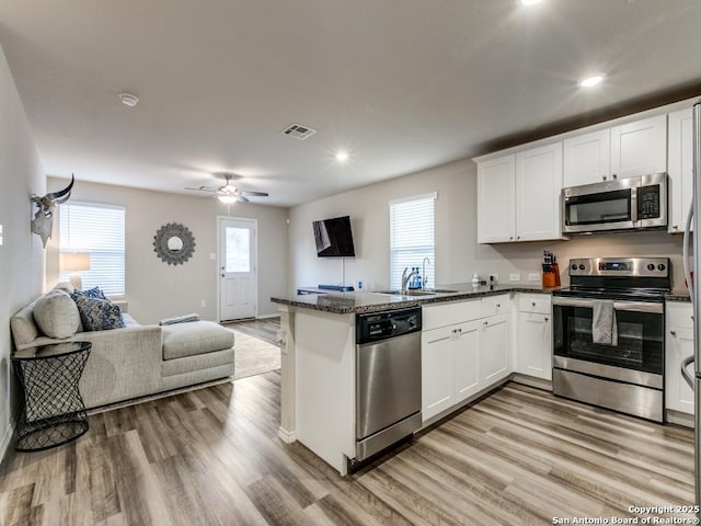 kitchen featuring light hardwood / wood-style floors, white cabinets, sink, kitchen peninsula, and stainless steel appliances