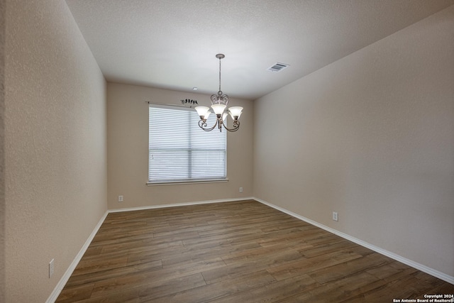 empty room with hardwood / wood-style flooring and a chandelier