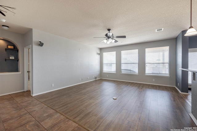 spare room with dark wood-type flooring, a textured ceiling, and ceiling fan