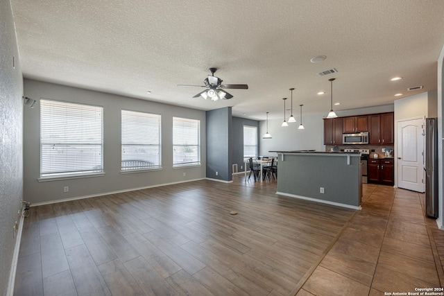 unfurnished living room with ceiling fan, dark wood-type flooring, and a textured ceiling