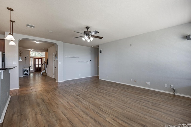 unfurnished living room with ceiling fan and dark wood-type flooring