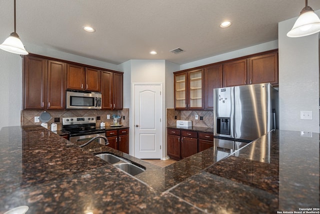 kitchen featuring sink, pendant lighting, dark stone counters, and appliances with stainless steel finishes