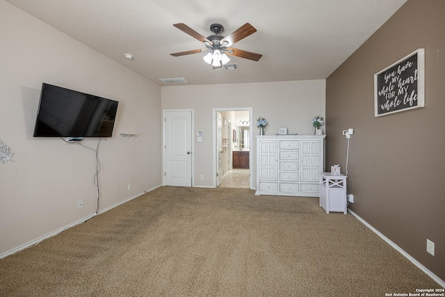 unfurnished bedroom featuring ceiling fan, light colored carpet, and ensuite bathroom