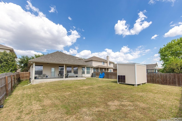 back of house with a patio area, a lawn, and a storage shed