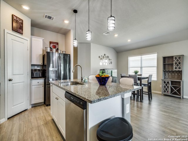 kitchen featuring sink, white cabinets, stainless steel appliances, and a kitchen island with sink