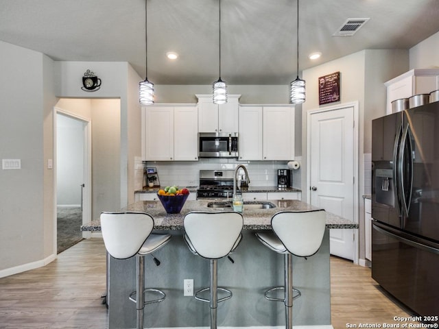 kitchen featuring decorative light fixtures, white cabinets, and appliances with stainless steel finishes