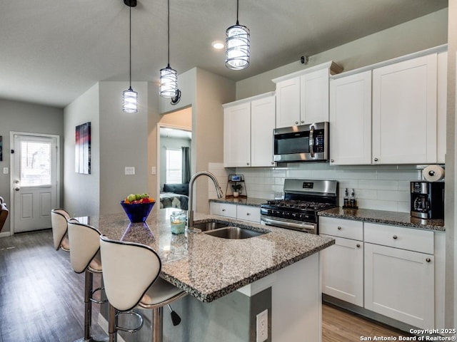 kitchen featuring sink, decorative light fixtures, a kitchen island with sink, and appliances with stainless steel finishes