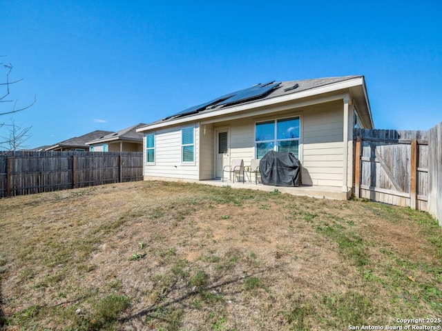 back of house featuring a lawn, solar panels, and a patio