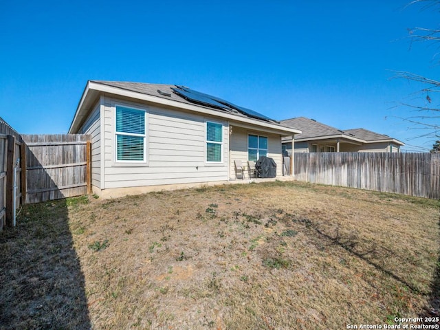 rear view of house with a lawn and solar panels