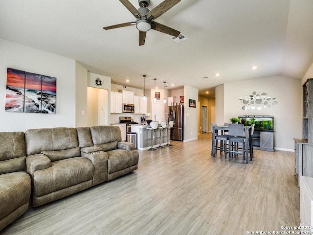 living room with light wood-type flooring, ceiling fan, and vaulted ceiling