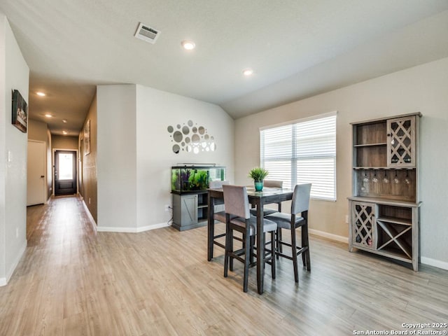 dining room with light wood-type flooring and vaulted ceiling