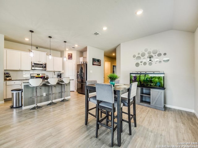 dining area with light hardwood / wood-style floors and lofted ceiling