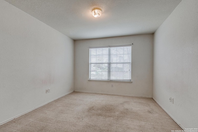 empty room with light colored carpet and a textured ceiling