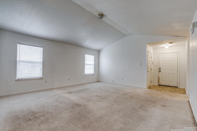 carpeted spare room featuring vaulted ceiling and a textured ceiling