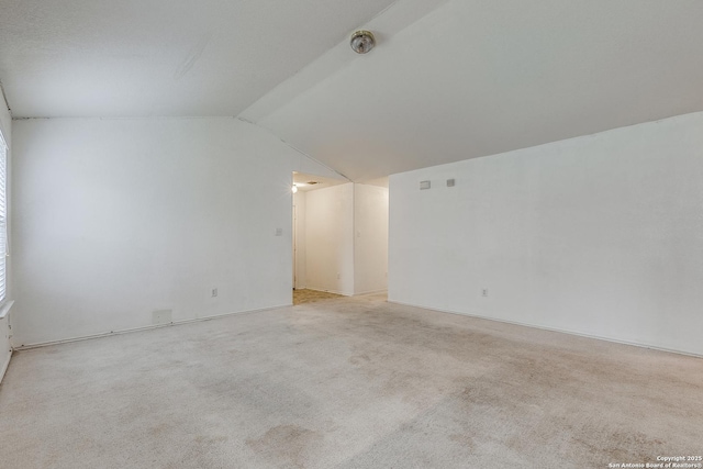 carpeted spare room featuring vaulted ceiling