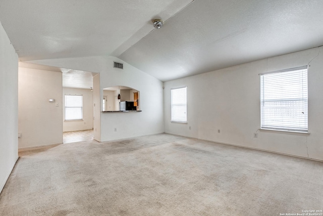 unfurnished living room featuring vaulted ceiling and light carpet