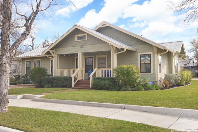 bungalow featuring covered porch and a front yard