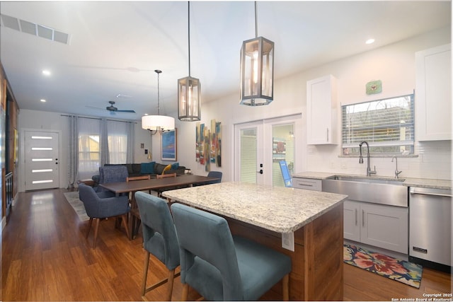 kitchen featuring white cabinets, a center island, decorative light fixtures, sink, and stainless steel dishwasher