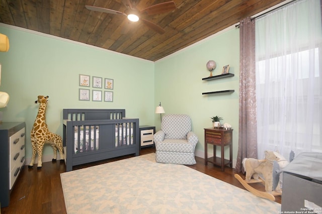 bedroom featuring wood ceiling, ceiling fan, a nursery area, and dark wood-type flooring