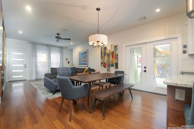 dining space featuring hardwood / wood-style flooring, ceiling fan with notable chandelier, and french doors