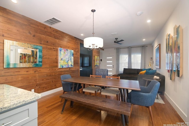 dining area with wood walls and light hardwood / wood-style flooring