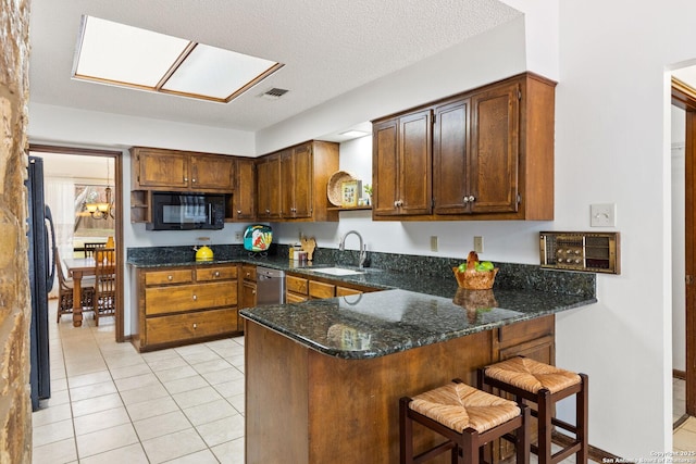 kitchen with black appliances, sink, kitchen peninsula, dark stone counters, and light tile patterned flooring