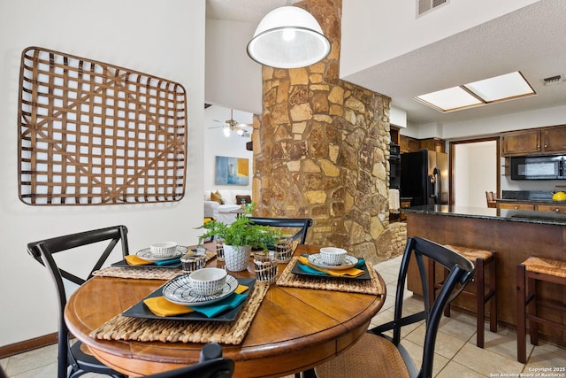 dining space featuring ceiling fan, a textured ceiling, light tile patterned floors, and a skylight