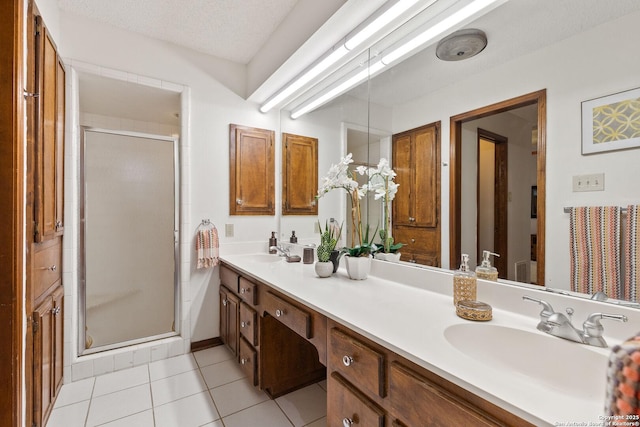 bathroom with a textured ceiling, tile patterned floors, a shower with door, and vanity