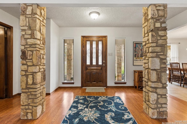 foyer with decorative columns, hardwood / wood-style flooring, and a textured ceiling