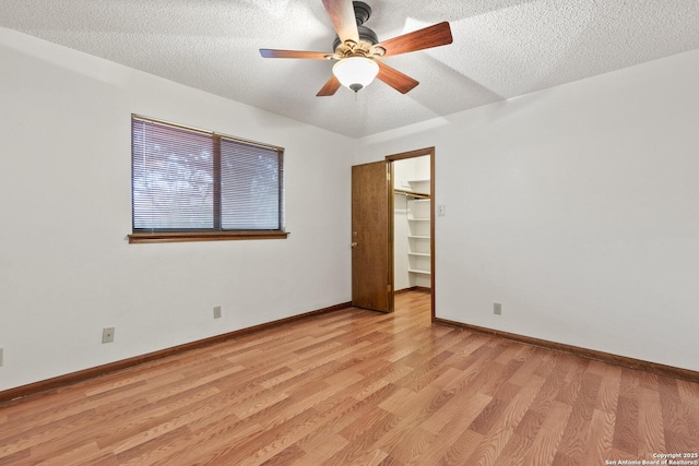 empty room featuring ceiling fan, a textured ceiling, and light wood-type flooring