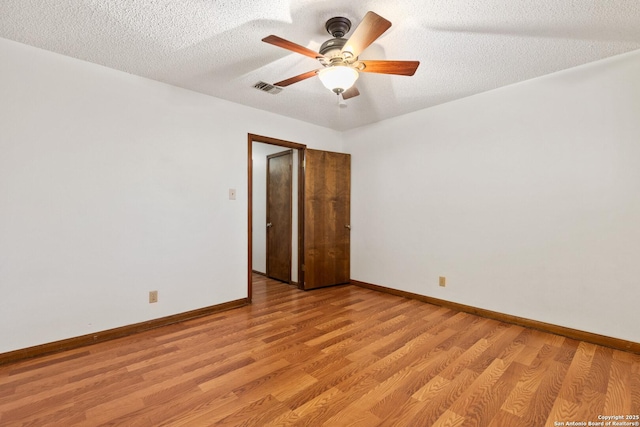 empty room featuring ceiling fan, light hardwood / wood-style floors, and a textured ceiling