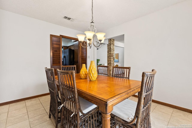 tiled dining area featuring decorative columns, an inviting chandelier, and a textured ceiling